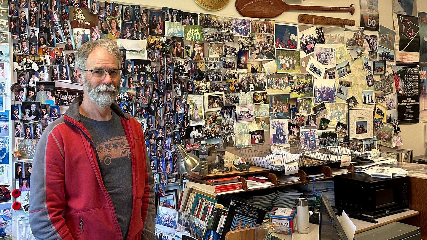 Timberline Teacher Stephen Joyce in front of his picture wall of former students.