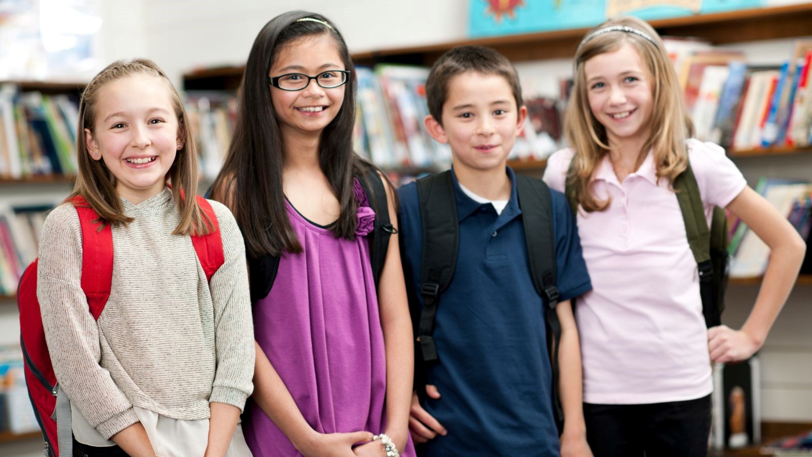 Smiling middle schoolers in front of library book shelves.